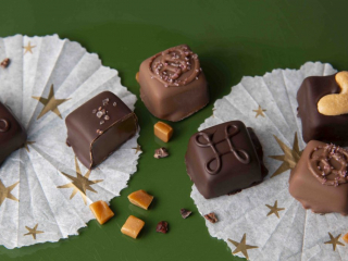 Dark and milk chocolate candies with carmel, salt and nuts on white paper with stars. Bonbons au chocolat noir et au lait avec caramel, sel et noix sur papier blanc avec &eacute;toiles.