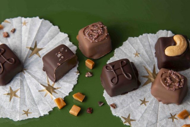 Dark and milk chocolate candies with carmel, salt and nuts on white paper with stars. Bonbons au chocolat noir et au lait avec caramel, sel et noix sur papier blanc avec étoiles.